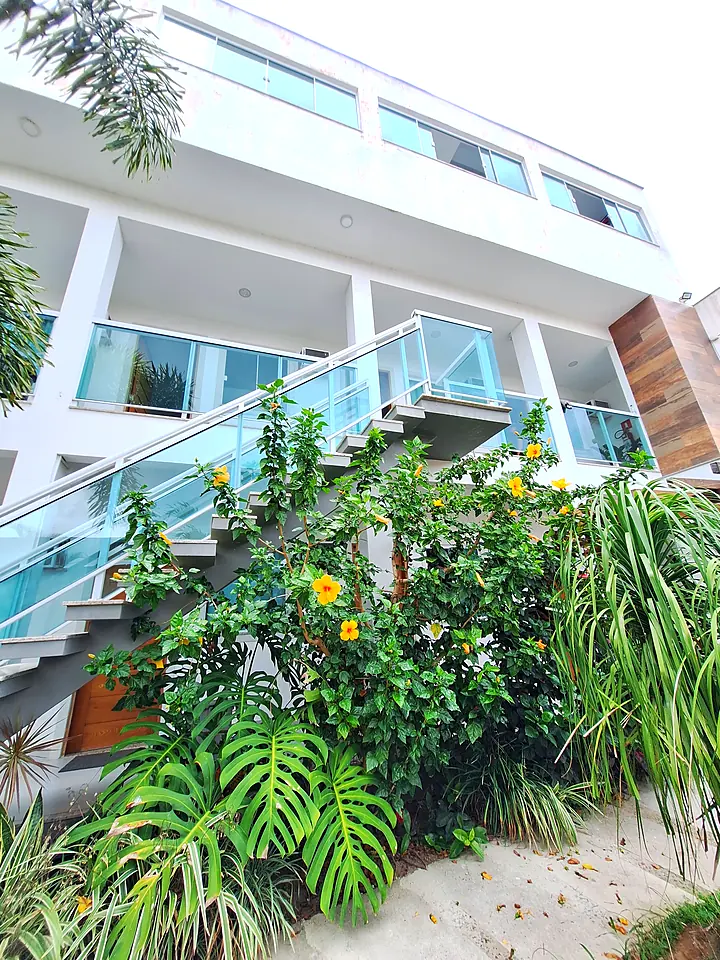 Jardim com hibiscos e a fachada de vidro da pousada