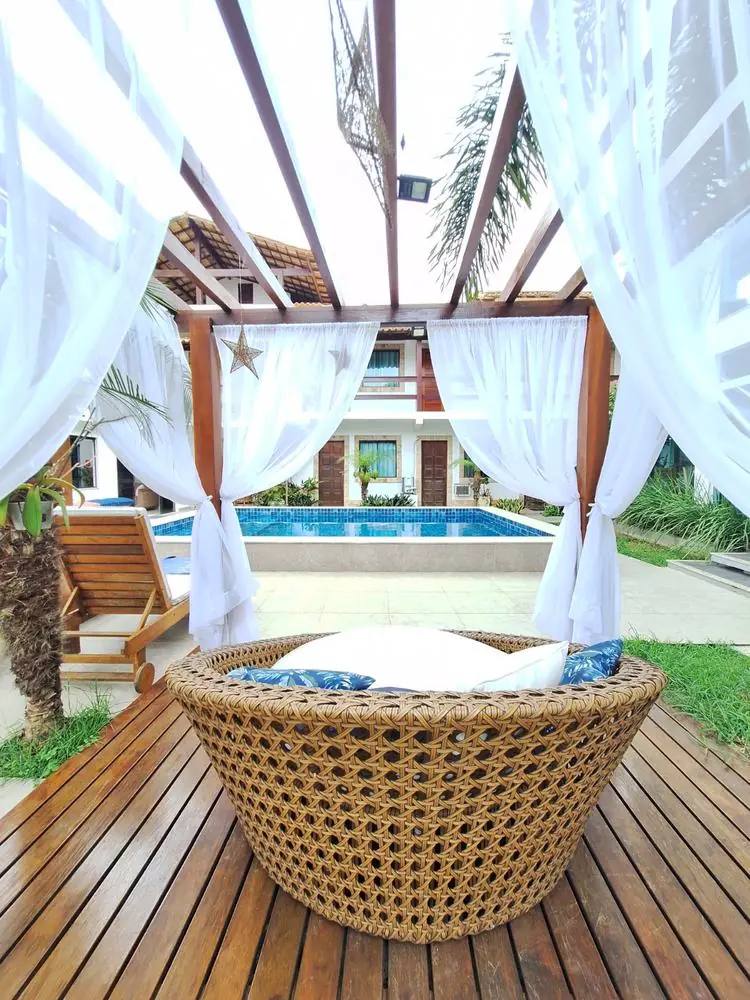 Cama balinesa sob o pergolado, com a piscina ao fundo