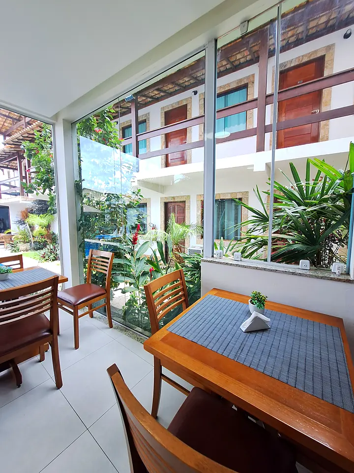 Salão do café da manhã com mesas e vista para o jardim