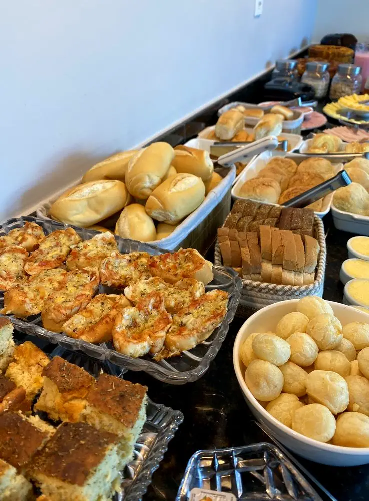 Mesa de café da manhã com pães, bolos e pão de queijo